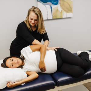 Physical therapist performing lumbopelvic mobility testing on a pregnant patient to assess range of motion and comfort.