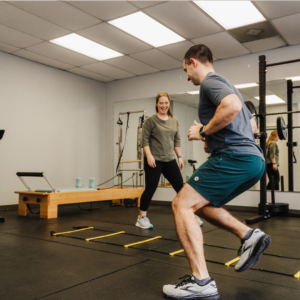 Physical therapist guiding a male patient through a workout to help him return to fitness without pain or discomfort.
