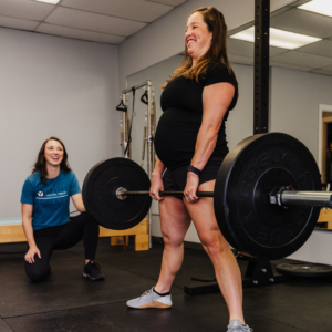Pregnant patient practicing proper lifting mechanics with guidance from her pelvic floor therapist, who is observing and providing instruction.
