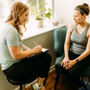Physical therapist discussing patient history and treatment goals during an initial evaluation.