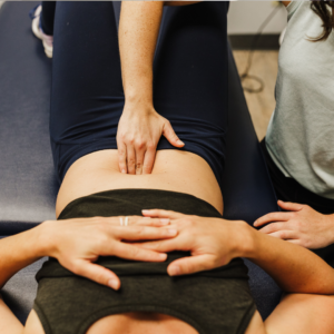 Pelvic floor therapist gently applying pressure and performing a bowel massage on a client to encourage digestion and relieve constipation.