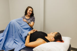 Pelvic floor therapist discussing with a patient, preparing her for a consent-based internal examination to assess for possible prolapse.