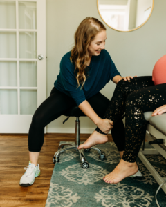 A pelvic floor therapist evaluates a patient’s body mechanics and mobility, assisting with targeted stretches to improve movement patterns.